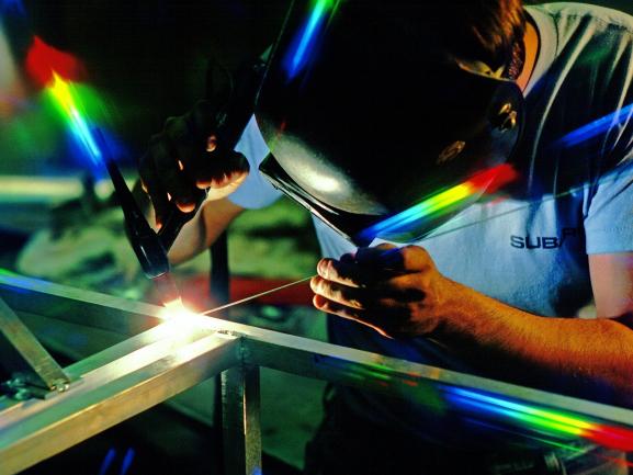 Image of engineer with work mask as bright light emits from a soldering iron